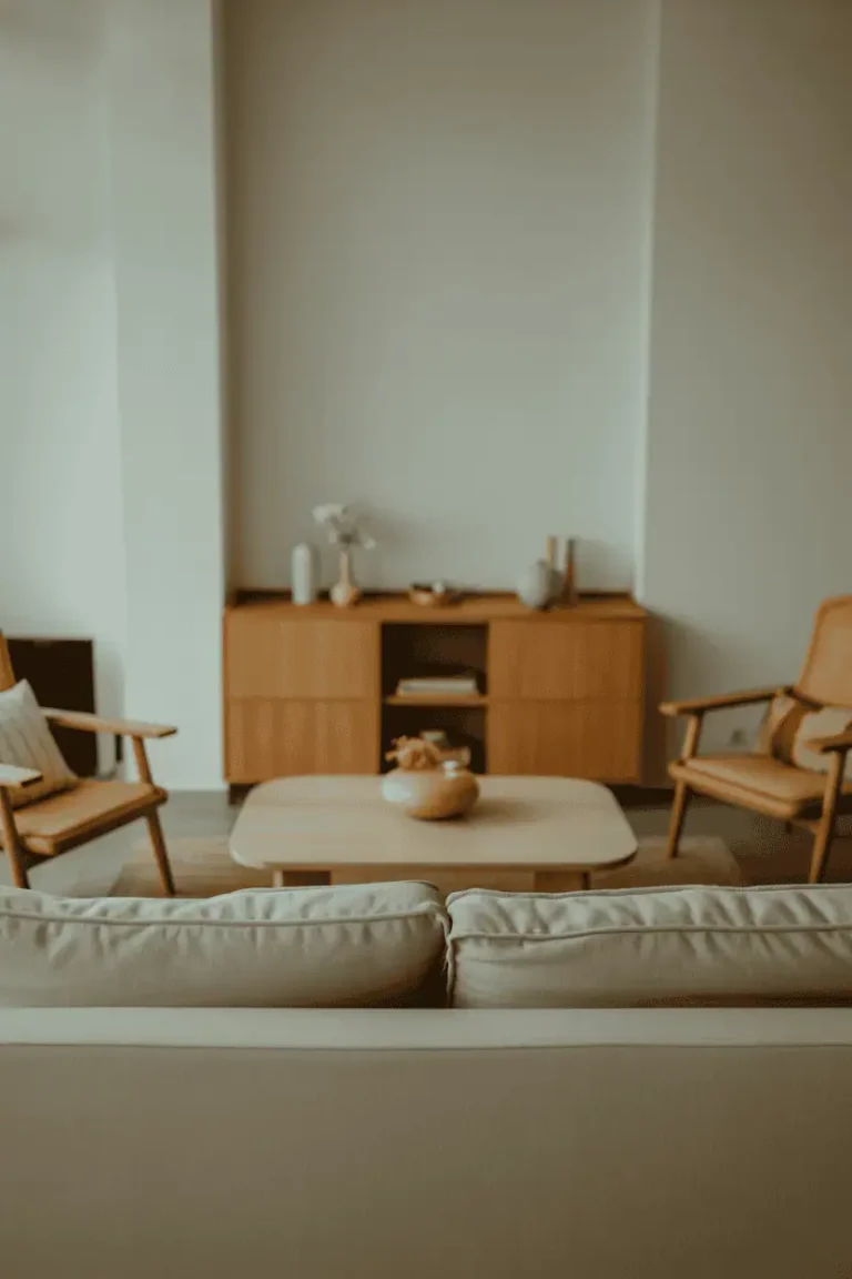 Minimalist living room with warm natural wood decor, calm and quiet atmosphere, light wood furniture, neutral walls, soft linen sofa, subtle textures, natural daylight filtering in, Scandinavian and Japanese-inspired aesthetic, realistic interior photography, editorial home magazine style, high resolution, balanced composition, warm neutral color palette, shallow depth of field, no people, no text, no watermark